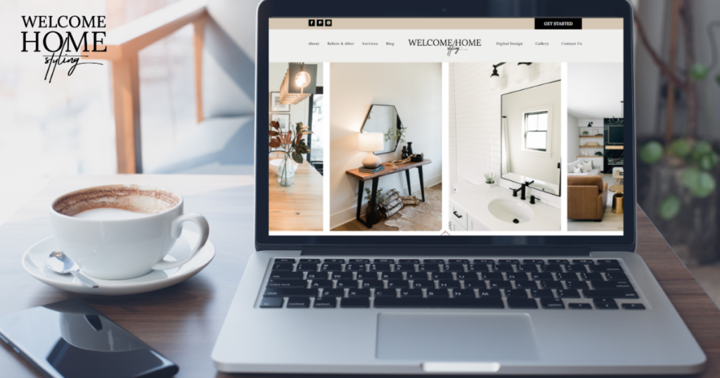 A stylish interior design website is pulled up on a laptop and is sitting next to a cup of coffee and a cell phone.