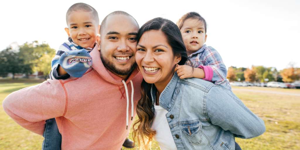 A family with two young children play in a park.